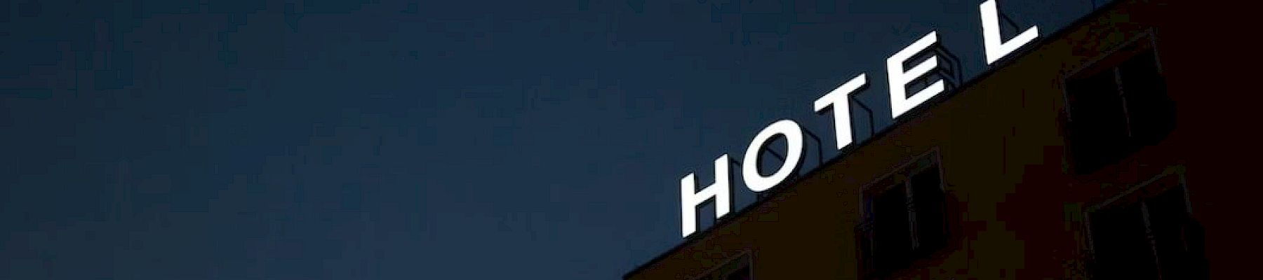 A dark hotel building with illuminated letters reading HOTEL against a night sky.