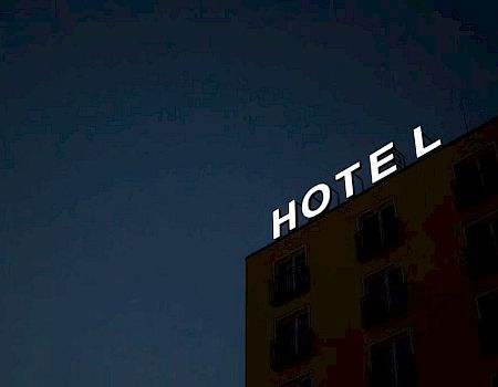 A dark hotel building with illuminated letters reading HOTEL against a night sky.